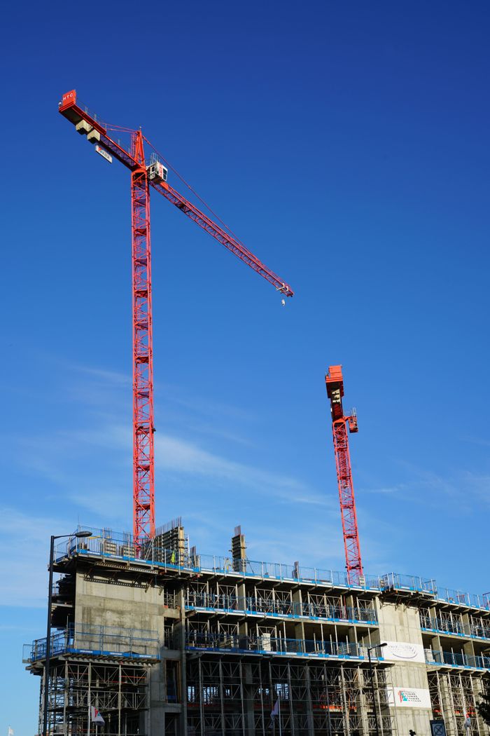Dynamic view of red tower cranes working at a construction site under blue skies.