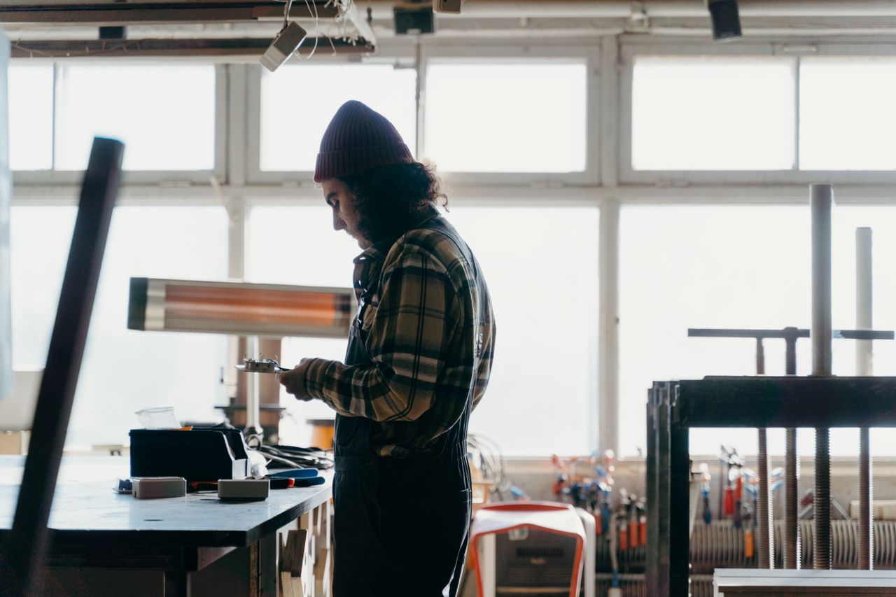 Craftsman focused on his work in a well-lit workshop, surrounded by tools.